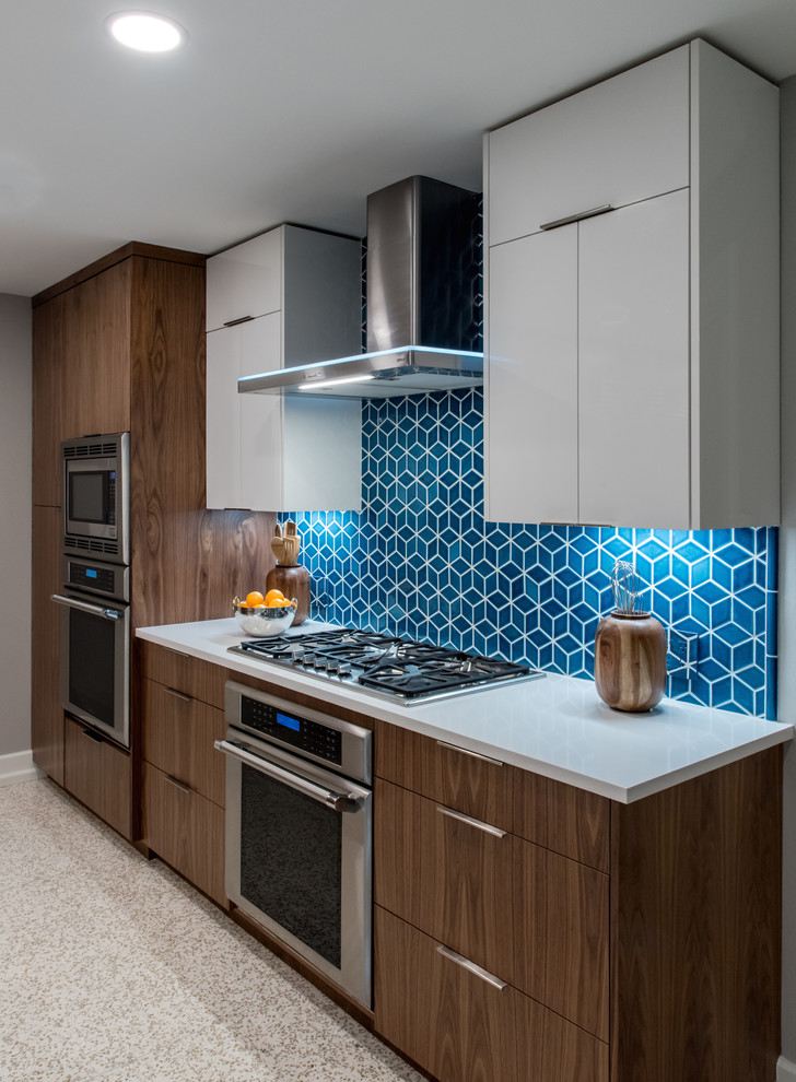 This is an example of a mid-sized midcentury l-shaped eat-in kitchen in Austin with medium wood cabinets, blue splashback, ceramic splashback, stainless steel appliances, with island, beige floor and grey benchtop.