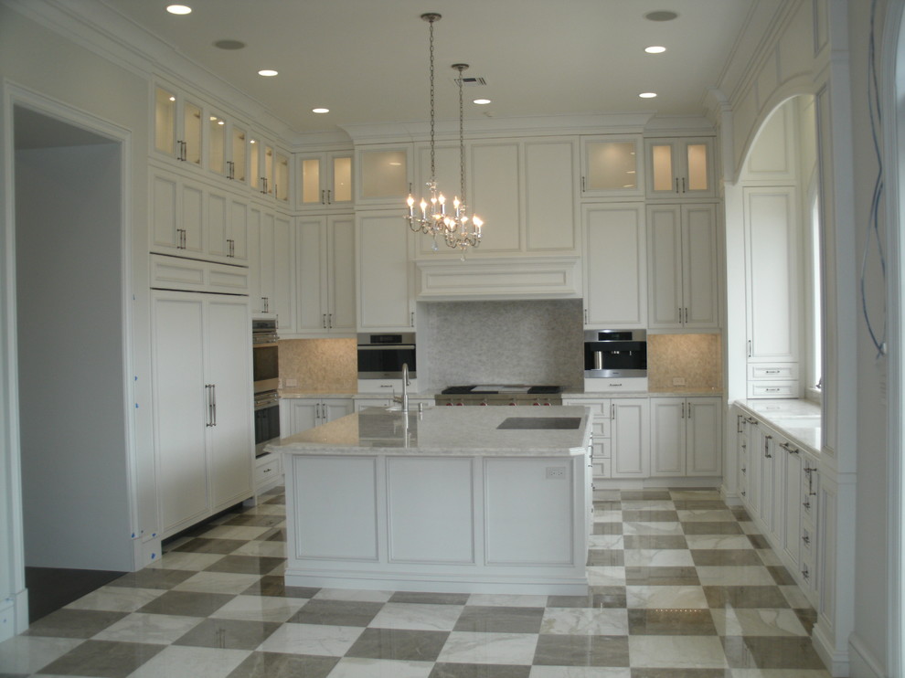 This is an example of a large transitional u-shaped kitchen in Miami with an undermount sink, white cabinets, panelled appliances, with island, recessed-panel cabinets, granite benchtops, beige splashback, mosaic tile splashback, vinyl floors and multi-coloured floor.