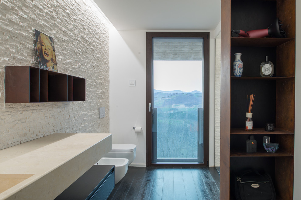 Photo of a mid-sized modern 3/4 bathroom in Other with flat-panel cabinets, black cabinets, a wall-mount toilet, white tile, travertine, white walls, painted wood floors, an integrated sink, marble benchtops, black floor and an open shower.