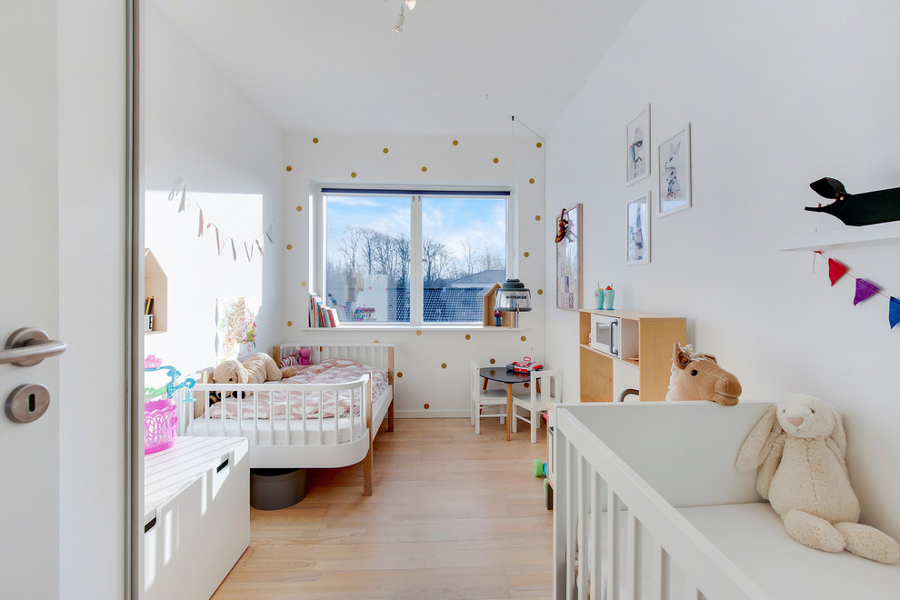 Scandinavian toddler room in Aalborg with white walls, light hardwood floors and beige floor for girls.