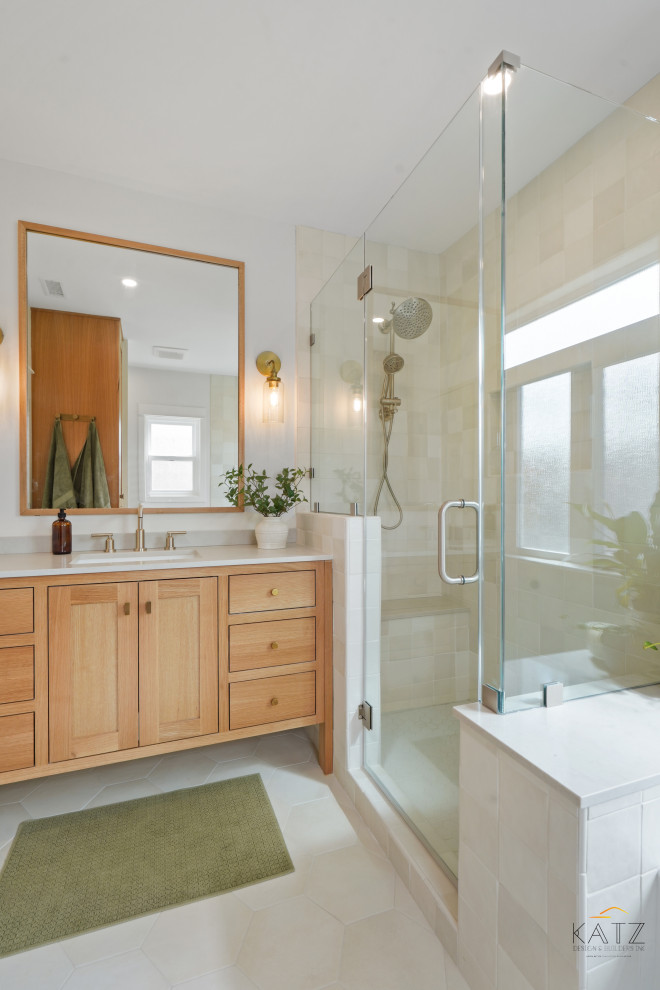This is an example of a beach style ensuite bathroom in Orange County with beaded cabinets, light wood cabinets, a corner bath, a corner shower, a one-piece toilet, beige tiles, beige walls, ceramic flooring, a submerged sink, beige floors, beige worktops, a single sink and a built in vanity unit.
