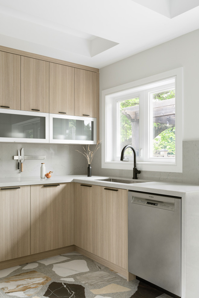 Inspiration for a small contemporary u-shaped kitchen in Toronto with an undermount sink, flat-panel cabinets, light wood cabinets, quartz benchtops, grey splashback, engineered quartz splashback, stainless steel appliances, porcelain floors, multi-coloured floor and grey benchtop.