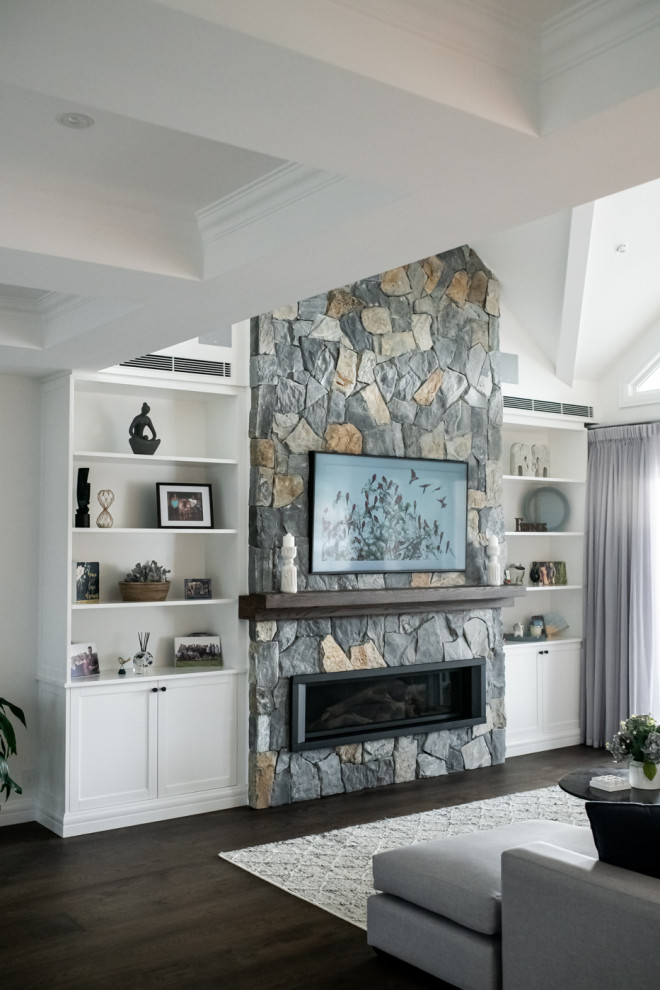 На фото: гостиная комната в стиле модернизм с горизонтальным камином, фасадом камина из камня, телевизором на стене и коричневым полом