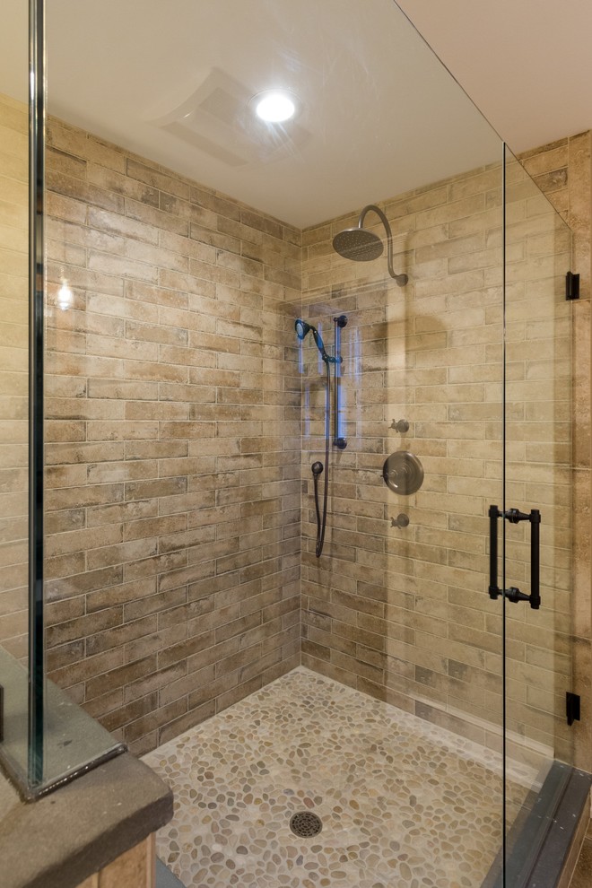 Cette photo montre une salle de bain nature en bois brun avec une douche ouverte, un carrelage beige, des carreaux de porcelaine, un sol en galet, un plan de toilette en stéatite et une cabine de douche à porte battante.