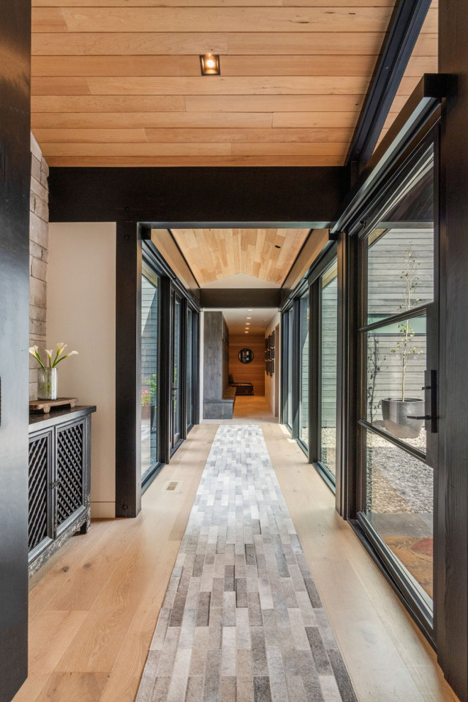 Inspiration for a large contemporary entry hall in Other with light hardwood floors, a pivot front door, a black front door, brown floor and wood.