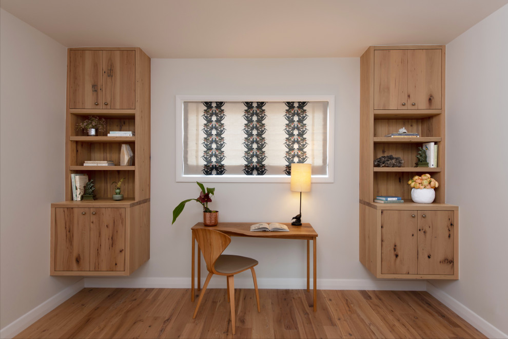Inspiration för mellanstora maritima arbetsrum, med ett bibliotek, vita väggar, ljust trägolv, ett fristående skrivbord och brunt golv