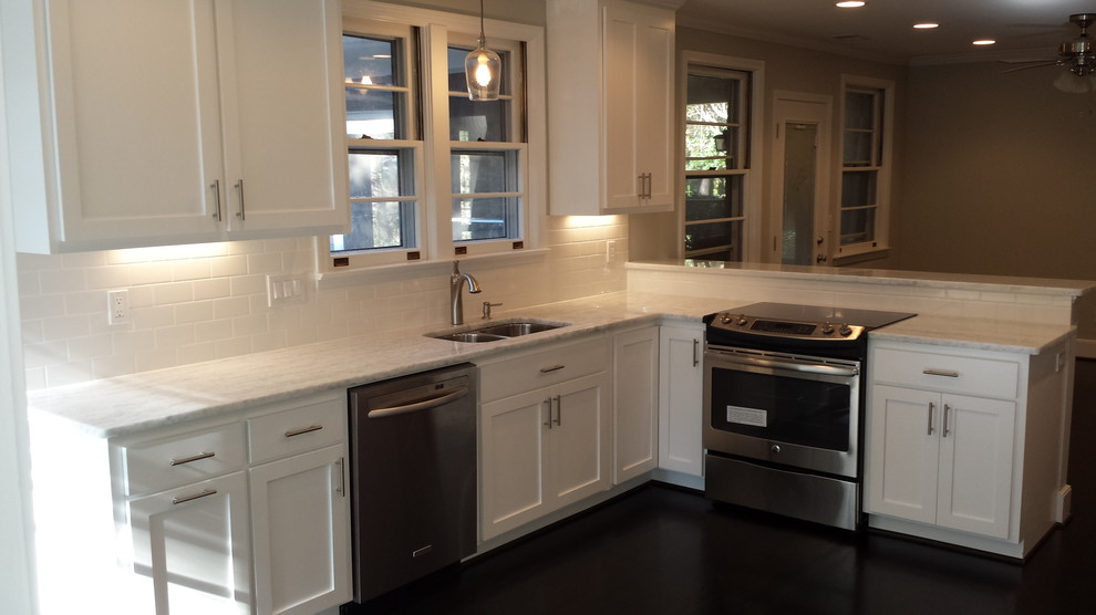 Inspiration for a mid-sized transitional l-shaped dark wood floor and brown floor kitchen pantry remodel with an undermount sink, shaker cabinets, white cabinets, marble countertops, white backsplash, subway tile backsplash, stainless steel appliances, a peninsula and white countertops