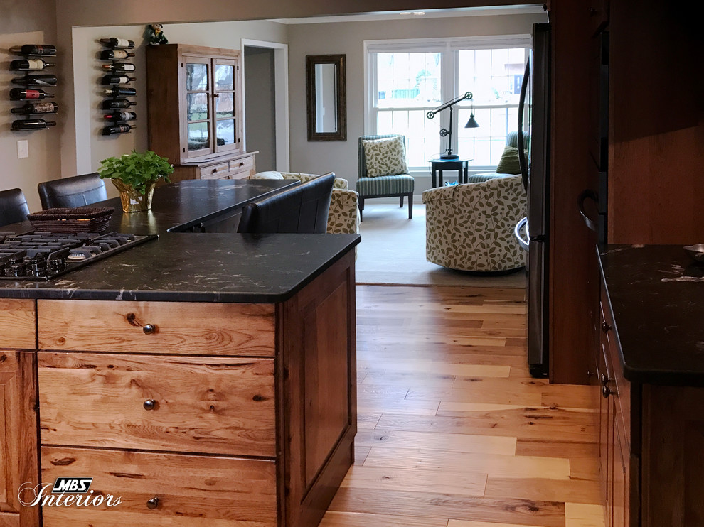 Inspiration for a large rustic l-shaped light wood floor and beige floor eat-in kitchen remodel with an undermount sink, raised-panel cabinets, medium tone wood cabinets, granite countertops, gray backsplash, ceramic backsplash, stainless steel appliances and an island