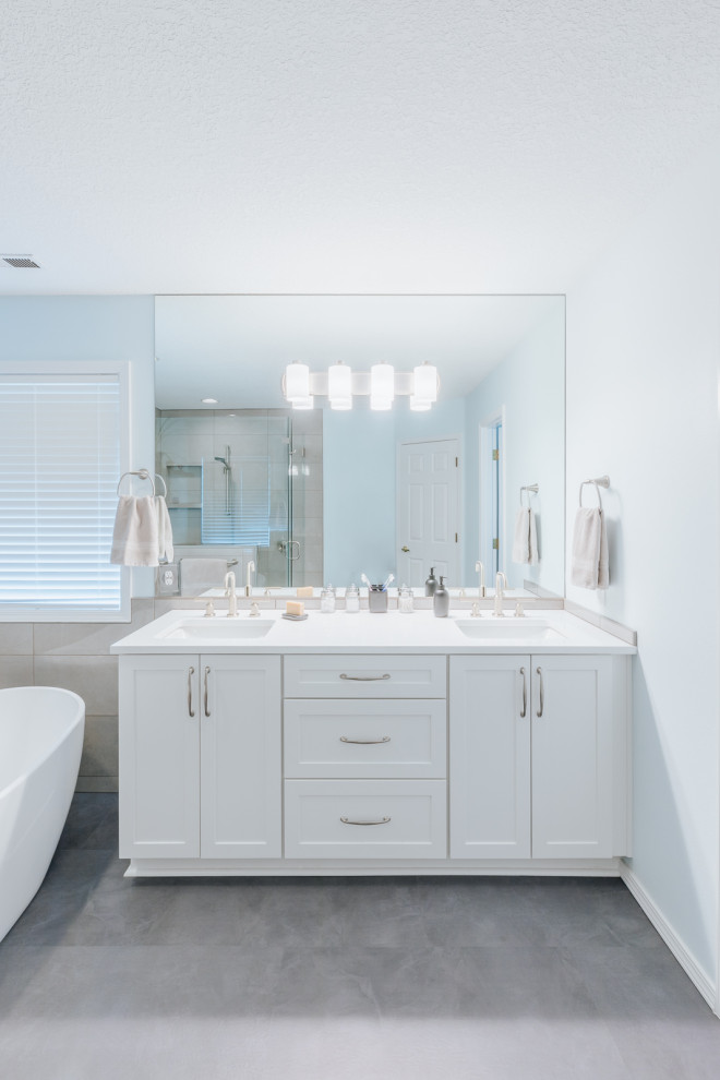 Inredning av ett modernt stort vit vitt en-suite badrum, med skåp i shakerstil, vita skåp, ett fristående badkar, en kantlös dusch, brun kakel, porslinskakel, blå väggar, vinylgolv, bänkskiva i kvartsit, grått golv och dusch med gångjärnsdörr