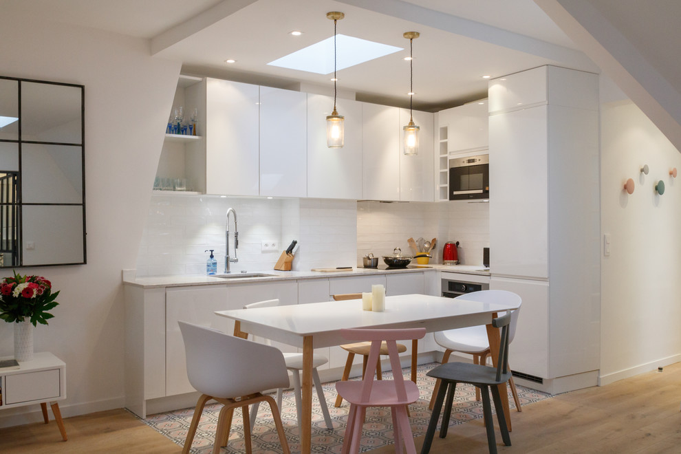 Inspiration for a small scandinavian l-shaped open plan kitchen in Los Angeles with an undermount sink, flat-panel cabinets, marble benchtops, white splashback, panelled appliances, cement tiles, white cabinets, no island and subway tile splashback.
