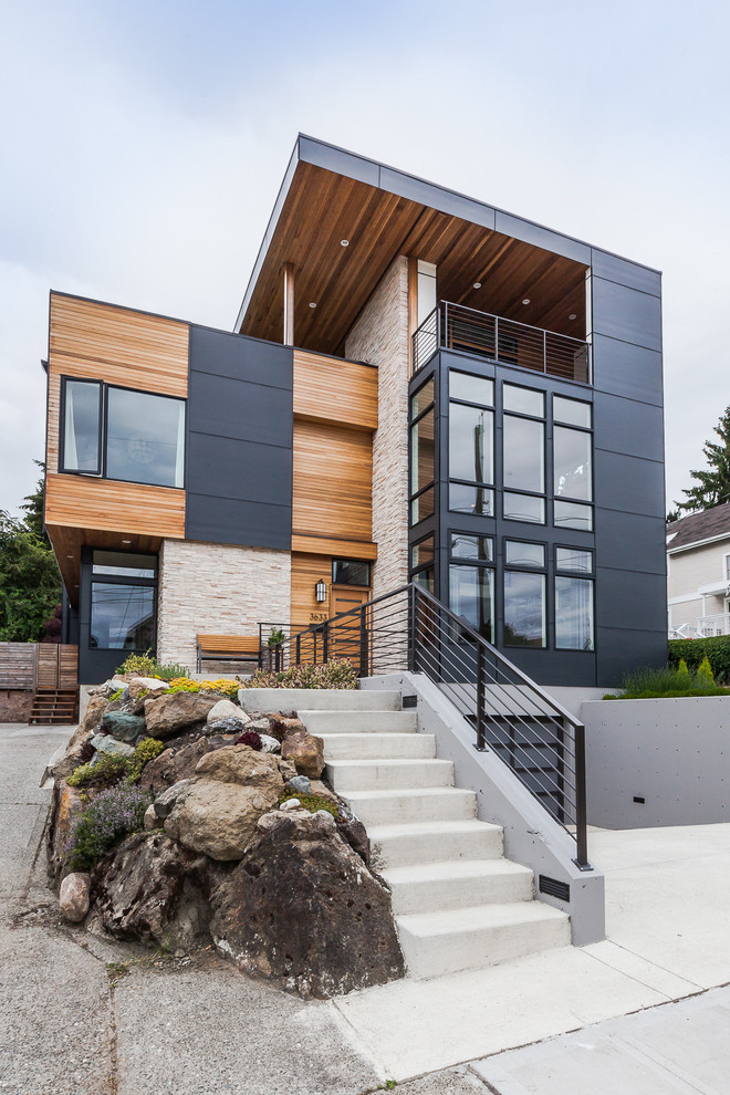 This is an example of a large contemporary three-storey grey exterior in Seattle with mixed siding and a flat roof.