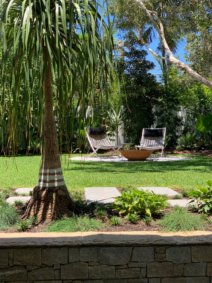 Cette photo montre un petit jardin arrière bord de mer avec un foyer extérieur, une exposition ensoleillée et une clôture en bois.