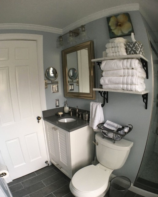Small transitional white tile and ceramic tile gray floor freestanding bathtub photo in Detroit with louvered cabinets, white cabinets, a two-piece toilet, blue walls, an undermount sink, solid surface countertops and a hinged shower door