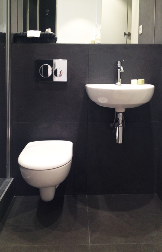 Photo of a small contemporary powder room in Paris with flat-panel cabinets, white cabinets, a wall-mount toilet, black tile, black walls and a wall-mount sink.