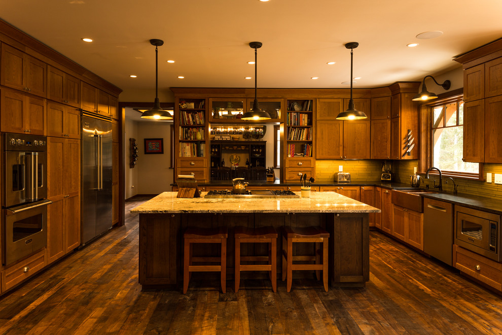 Eat-in kitchen - large rustic u-shaped dark wood floor and brown floor eat-in kitchen idea with a farmhouse sink, shaker cabinets, medium tone wood cabinets, granite countertops, green backsplash, glass tile backsplash, stainless steel appliances and an island