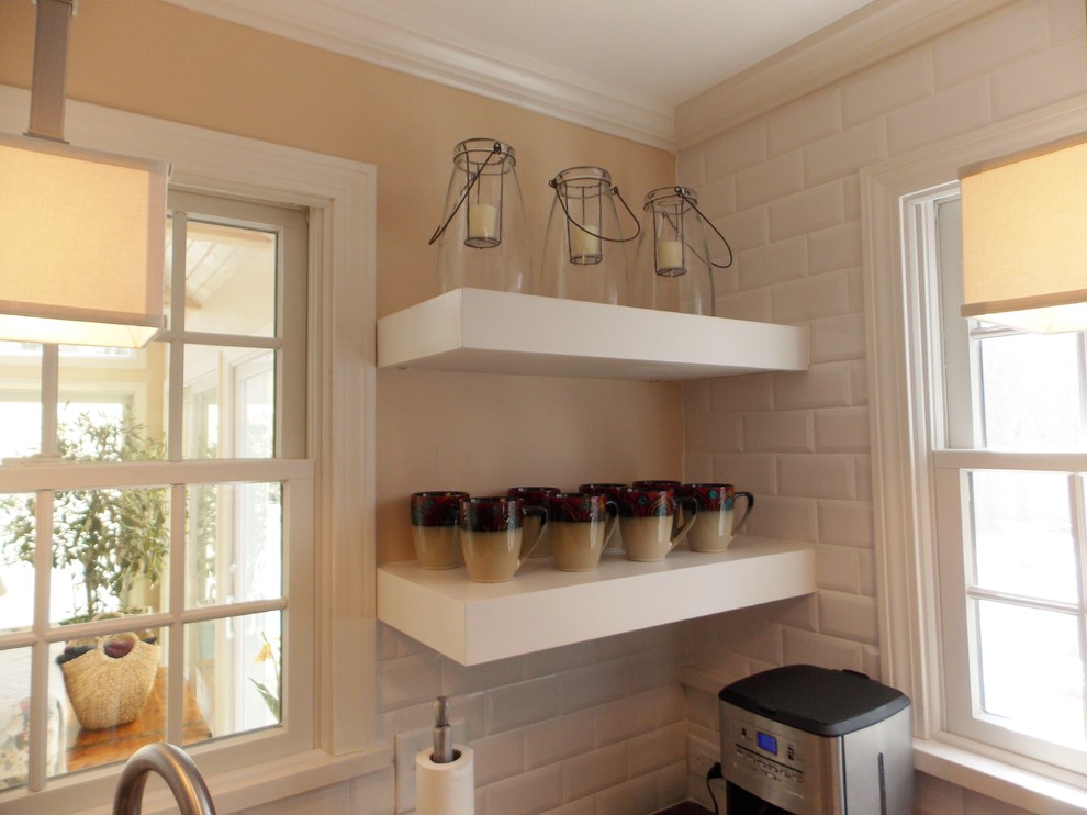Example of a small transitional u-shaped medium tone wood floor eat-in kitchen design in Boston with an undermount sink, shaker cabinets, white cabinets, solid surface countertops, white backsplash, ceramic backsplash, stainless steel appliances and beige walls