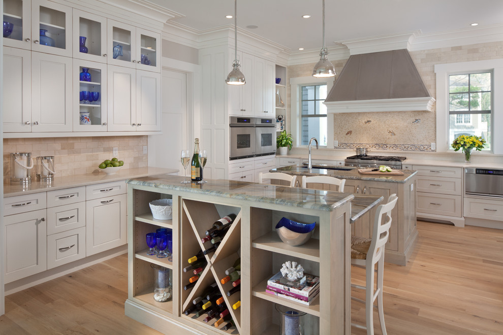 Photo of a beach style u-shaped kitchen in DC Metro with recessed-panel cabinets, white cabinets, beige splashback, stainless steel appliances, medium hardwood floors and multiple islands.