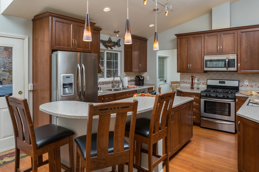 Kitchen pantry - mid-sized transitional u-shaped medium tone wood floor kitchen pantry idea with an undermount sink, recessed-panel cabinets, medium tone wood cabinets, solid surface countertops, beige backsplash, mosaic tile backsplash, stainless steel appliances and an island