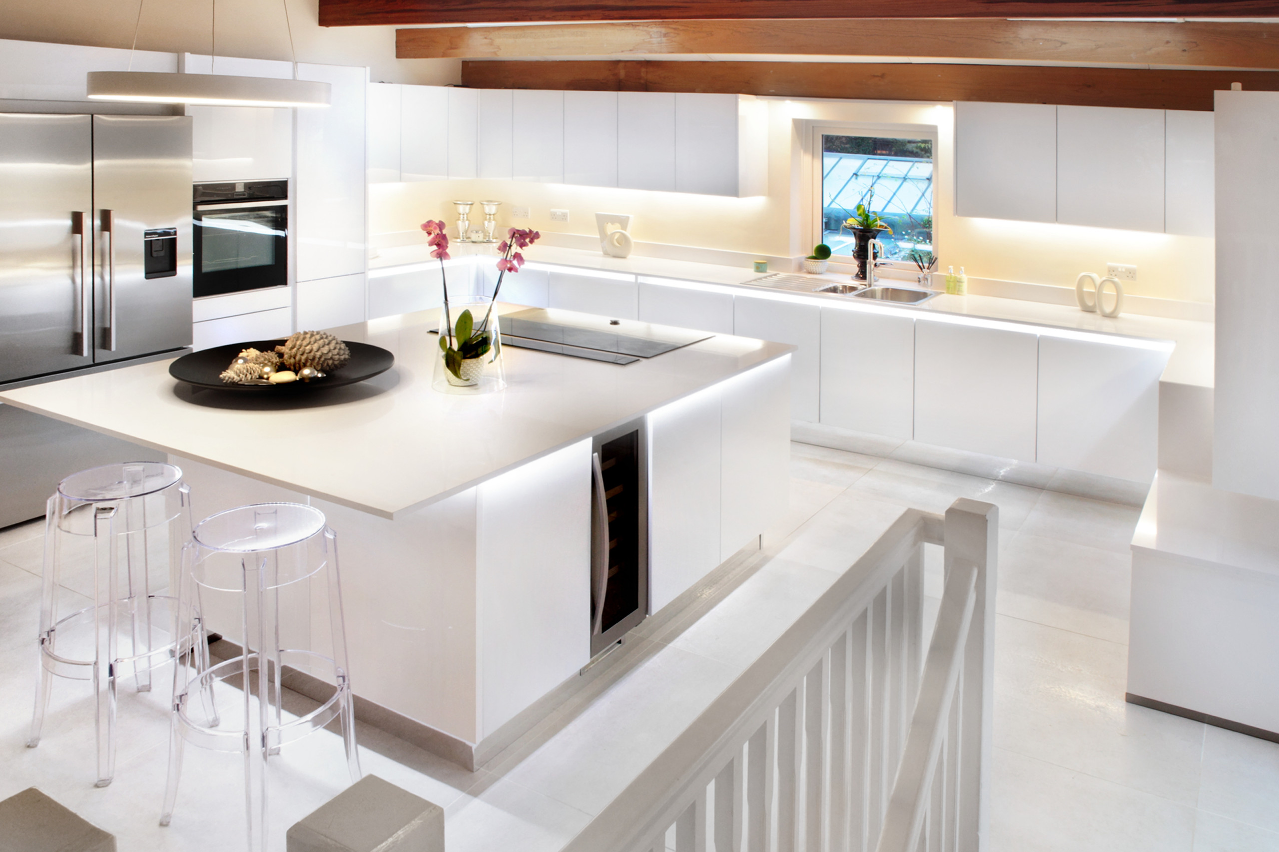 Example of a large trendy u-shaped limestone floor, white floor and exposed beam open concept kitchen design in Oxfordshire with flat-panel cabinets, white cabinets, quartzite countertops, stainless s