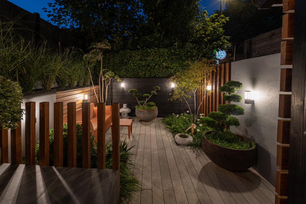 Réalisation d'un petit jardin design au printemps avec une exposition partiellement ombragée et une terrasse en bois.
