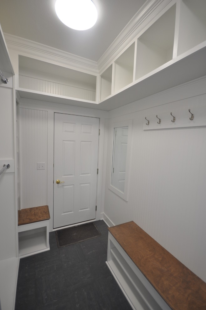 Inspiration for a small traditional galley utility room in Other with raised-panel cabinets, white cabinets, laminate benchtops, yellow walls, ceramic floors and a stacked washer and dryer.