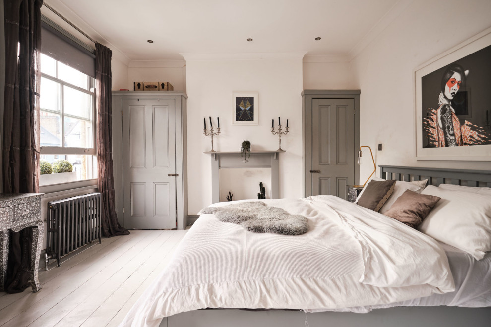 Cette image montre une chambre parentale grise et blanche bohème de taille moyenne avec un mur blanc, parquet peint, une cheminée standard, un manteau de cheminée en bois et un sol blanc.