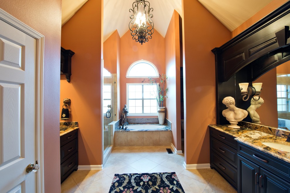 This is an example of a large transitional master bathroom in Little Rock with an undermount sink, raised-panel cabinets, dark wood cabinets, granite benchtops, an undermount tub, a double shower, a one-piece toilet, beige tile, porcelain tile, orange walls and porcelain floors.