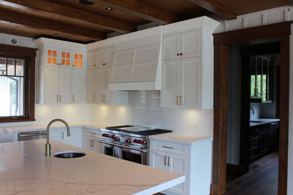 Inspiration for a large rustic u-shaped dark wood floor, brown floor and wood ceiling eat-in kitchen remodel in Toronto with a farmhouse sink, shaker cabinets, white cabinets, quartz countertops, white backsplash, subway tile backsplash, stainless steel appliances, an island and white countertops