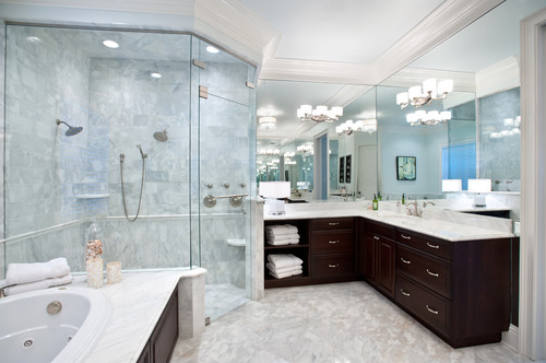 Marble-effect tilework throughout this bespoke bathroom makes the deep, rich color of the L-shaped vanity really stand out. Note the massive walk-in glass shower.