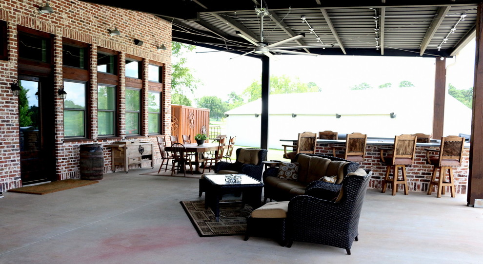 This is an example of a large industrial front yard verandah in Houston with an outdoor kitchen, concrete slab and a roof extension.