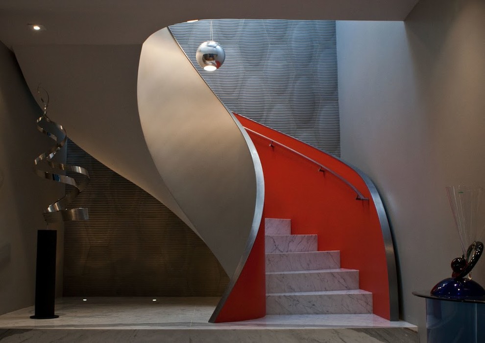 Photo of a large eclectic marble curved staircase in San Francisco with marble risers and metal railing.