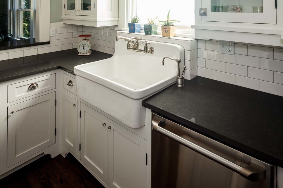 Inspiration for a large transitional dark wood floor kitchen remodel with a farmhouse sink, recessed-panel cabinets, white cabinets, granite countertops, white backsplash, subway tile backsplash, stainless steel appliances and an island