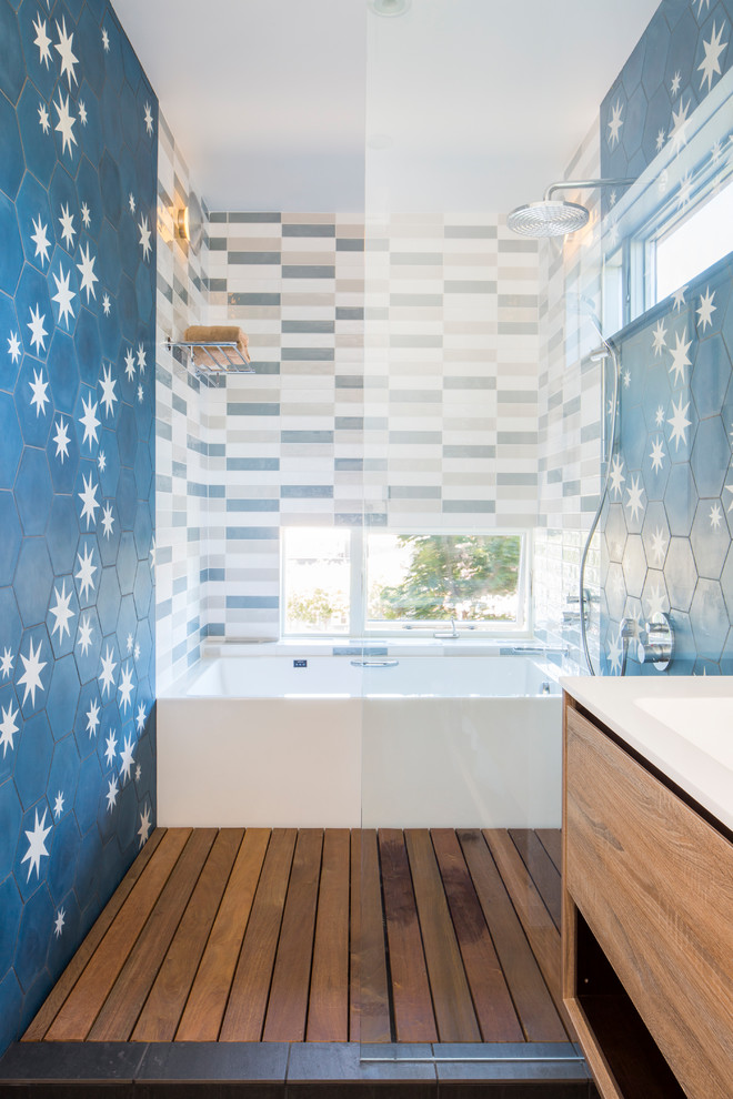 This is an example of a contemporary wet room bathroom in Seattle with flat-panel cabinets, light wood cabinets, an alcove tub, multi-coloured tile, multi-coloured walls and white benchtops.