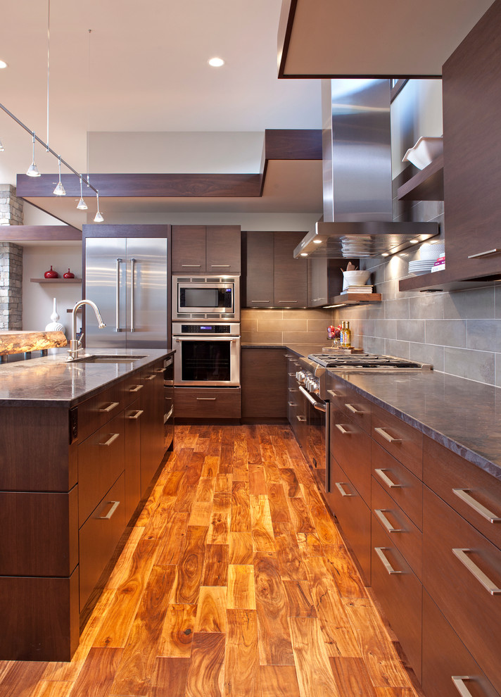 Contemporary l-shaped kitchen in Minneapolis with flat-panel cabinets, dark wood cabinets, grey splashback and stainless steel appliances.