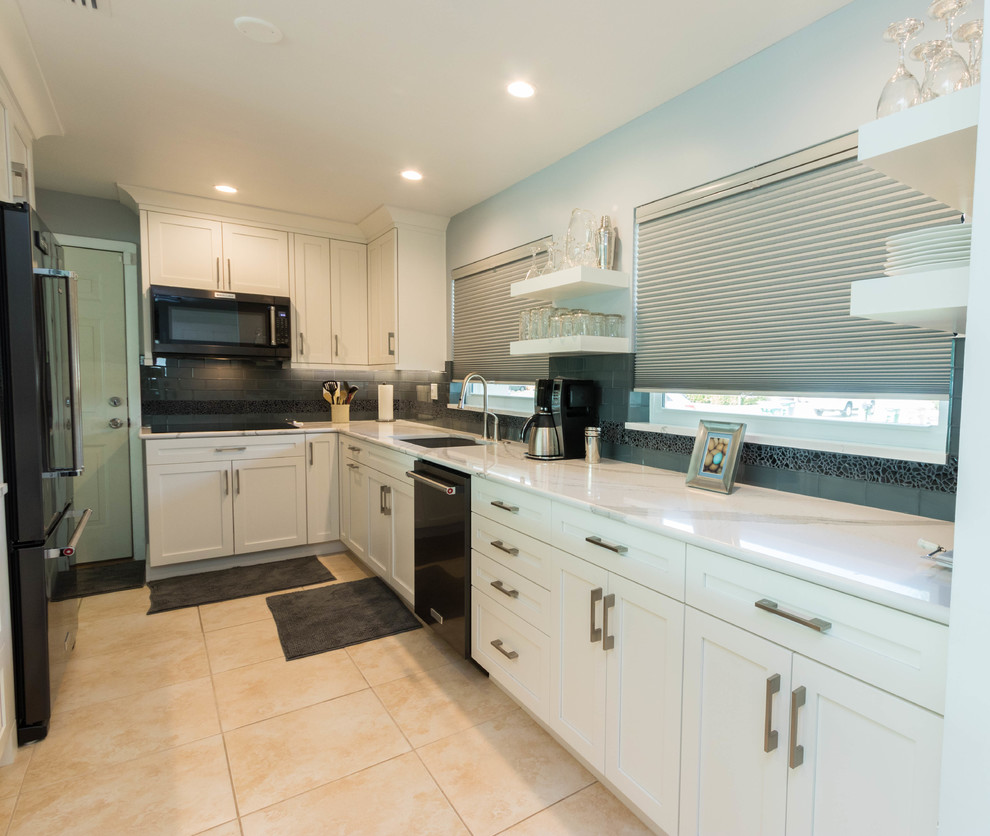 Mid-sized transitional galley ceramic tile open concept kitchen photo in Miami with a single-bowl sink, shaker cabinets, white cabinets, quartz countertops, black backsplash, glass tile backsplash, black appliances and a peninsula