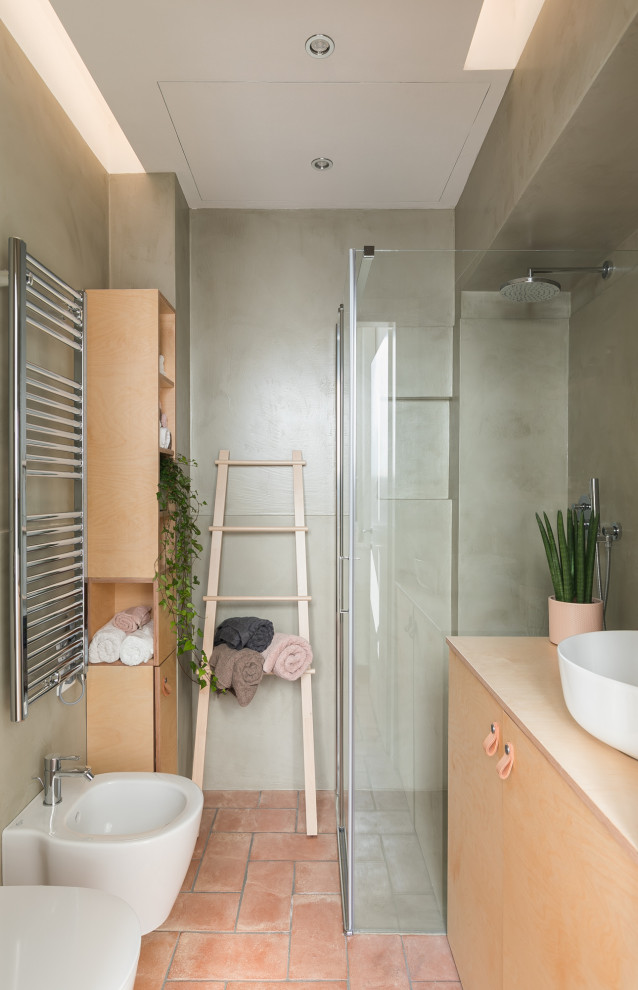 Inredning av ett modernt litet gul gult badrum med dusch, med luckor med profilerade fronter, skåp i ljust trä, en kantlös dusch, en vägghängd toalettstol, grön kakel, gröna väggar, tegelgolv, ett fristående handfat, träbänkskiva, rött golv och dusch med gångjärnsdörr