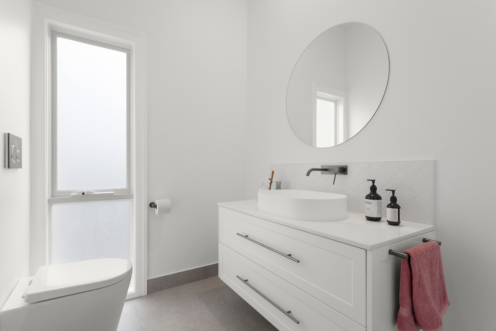 Design ideas for a mid-sized contemporary bathroom in Melbourne with shaker cabinets, white cabinets, a wall-mount toilet, white tile, ceramic tile, white walls, ceramic floors, engineered quartz benchtops, grey floor, white benchtops, a single vanity and a floating vanity.