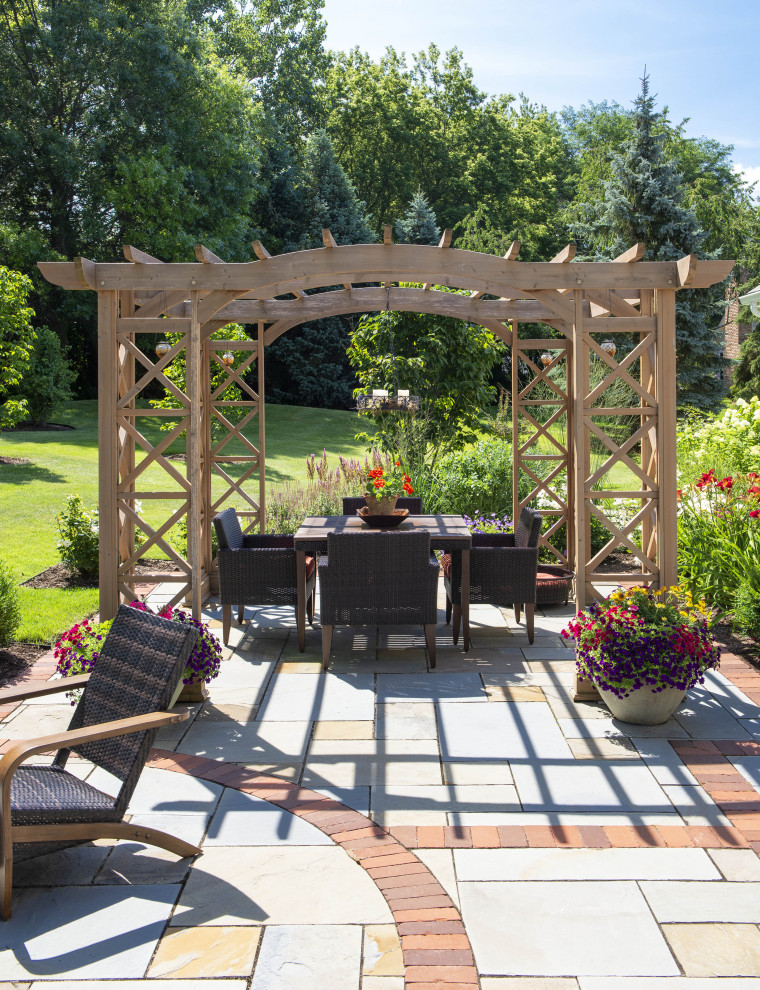 Inspiration for a large traditional backyard patio in Milwaukee with natural stone pavers and a pergola.