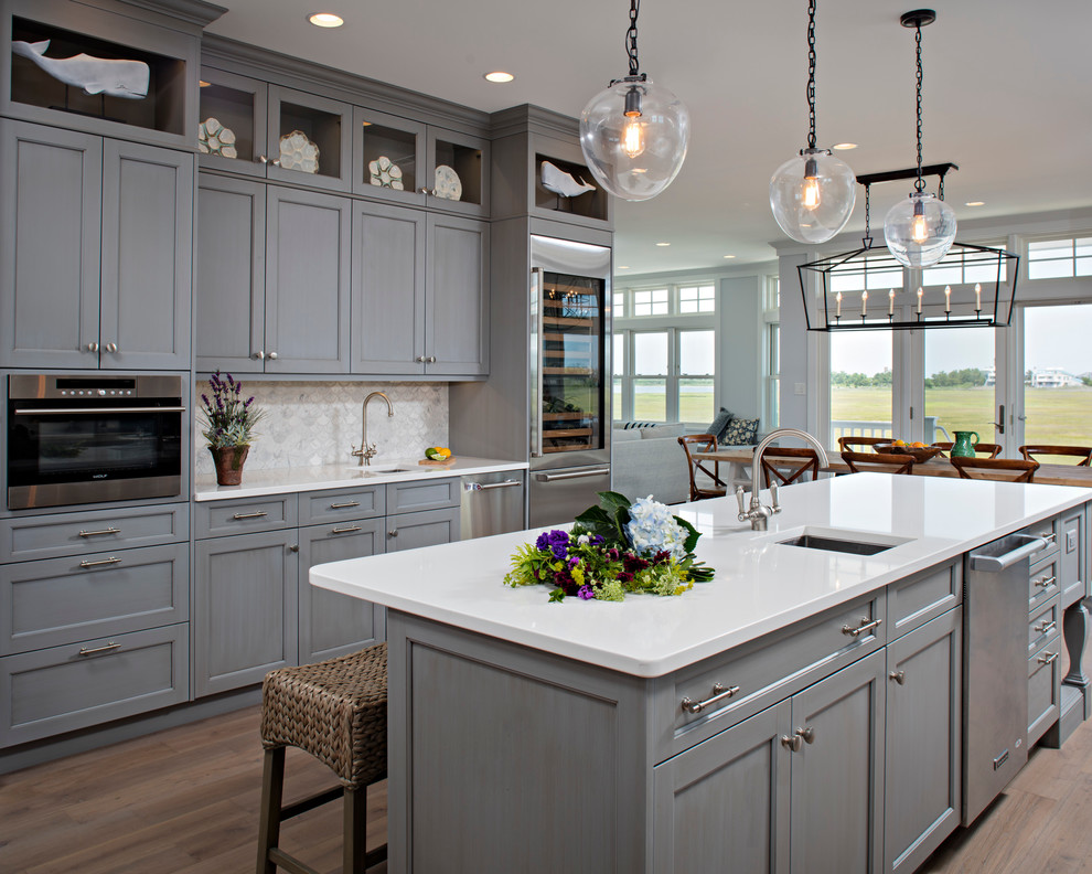 Open concept kitchen - large transitional l-shaped medium tone wood floor open concept kitchen idea with an undermount sink, recessed-panel cabinets, gray cabinets, quartz countertops, gray backsplash, stainless steel appliances, an island and porcelain backsplash