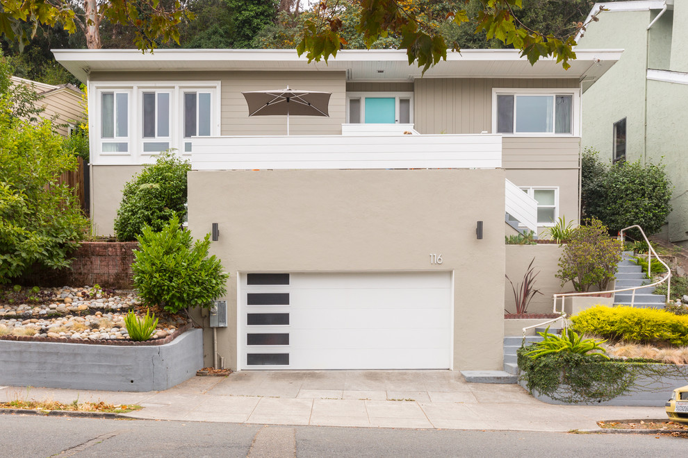 This is an example of a mid-sized midcentury two-storey stucco beige house exterior in San Francisco with a flat roof.