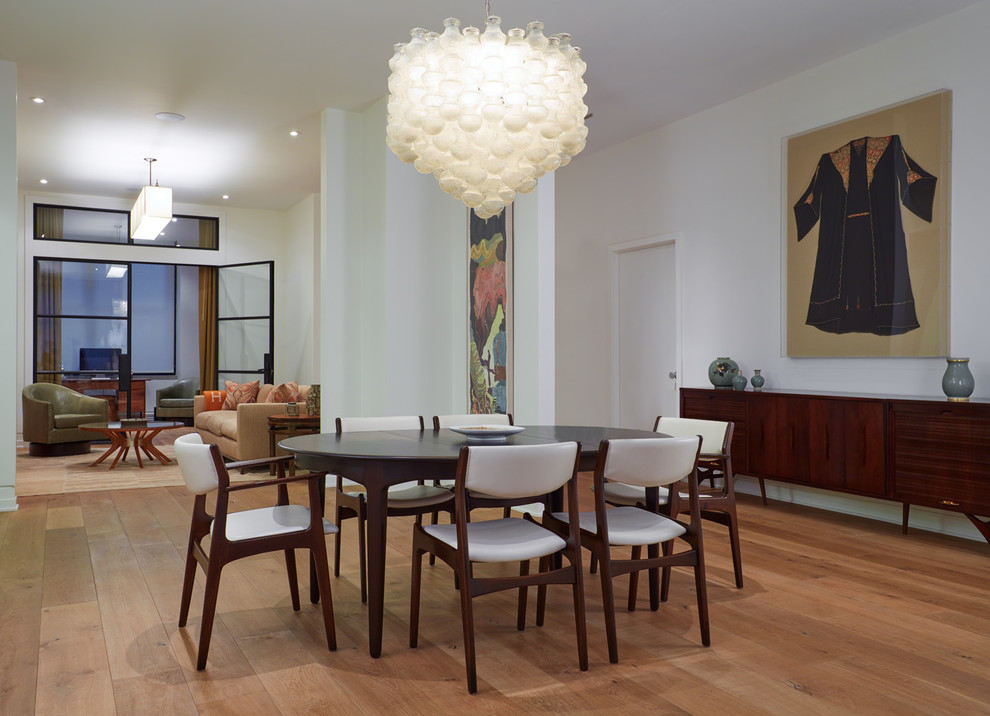 This is an example of a mid-sized contemporary open plan dining in New York with white walls, light hardwood floors, brown floor and no fireplace.