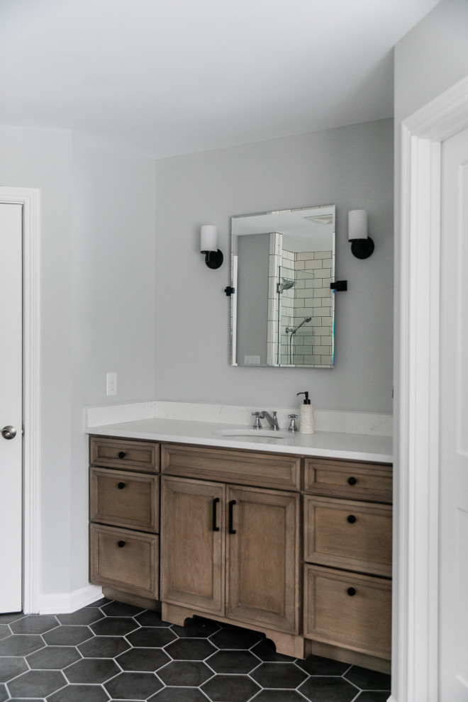 Inspiration for a mid-sized modern master bathroom in Other with raised-panel cabinets, medium wood cabinets, a claw-foot tub, an open shower, a one-piece toilet, white tile, subway tile, grey walls, ceramic floors, an undermount sink, engineered quartz benchtops, black floor, a hinged shower door and white benchtops.