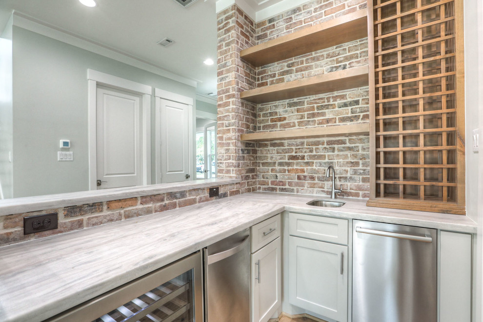 Mid-sized transitional l-shaped wet bar in Houston with an undermount sink, shaker cabinets, white cabinets, marble benchtops, red splashback, brick splashback, light hardwood floors and brown floor.