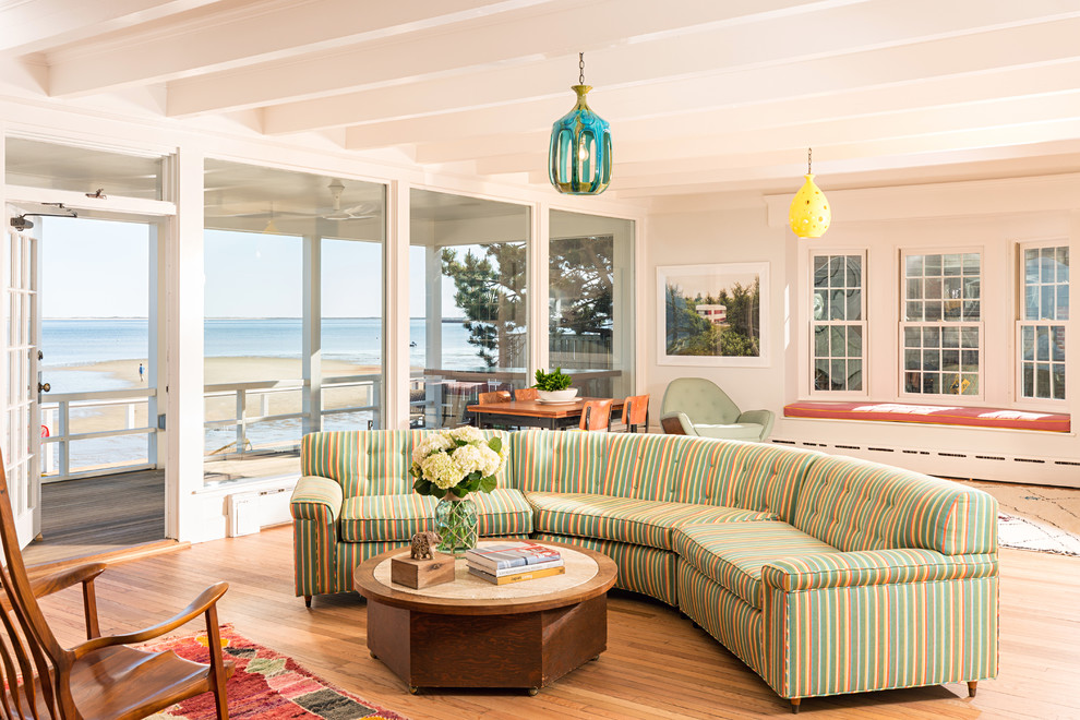 This is an example of a beach style open concept living room in Boston with white walls and light hardwood floors.