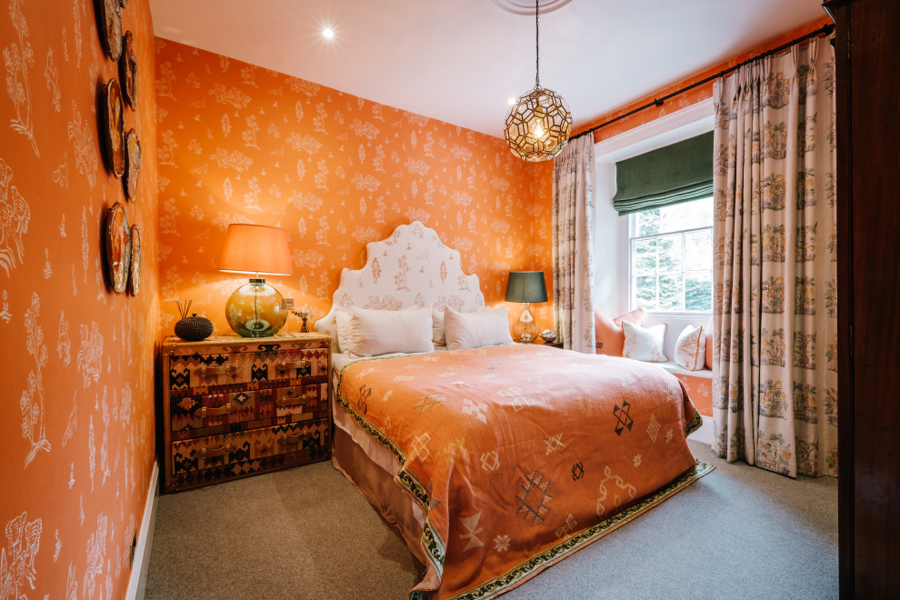 Imagen de dormitorio bohemio con parades naranjas, moqueta, suelo gris y papel pintado