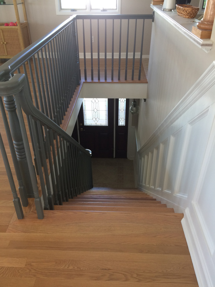 This is an example of a large beach style wood straight staircase in Philadelphia with painted wood risers and wood railing.