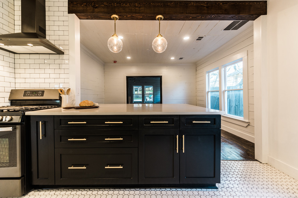 Design ideas for a midcentury galley kitchen in Dallas with a farmhouse sink, shaker cabinets, black cabinets, quartz benchtops, white splashback, ceramic splashback, stainless steel appliances and ceramic floors.