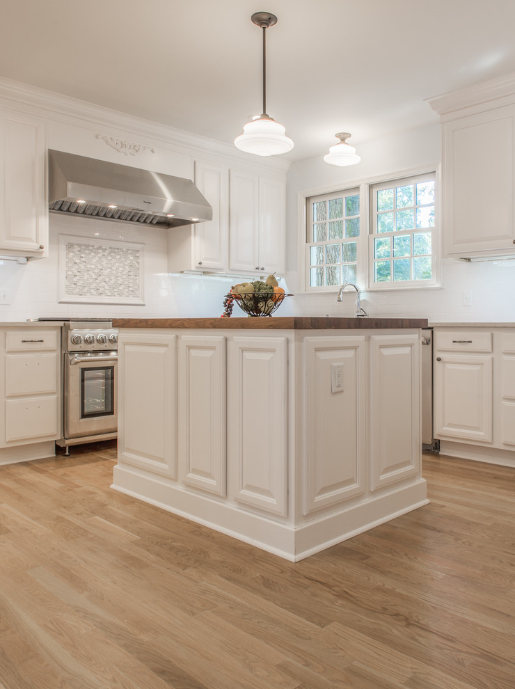 Design ideas for a traditional kitchen in Jacksonville with a double-bowl sink, white cabinets, quartz benchtops, white splashback, subway tile splashback, stainless steel appliances, light hardwood floors and with island.