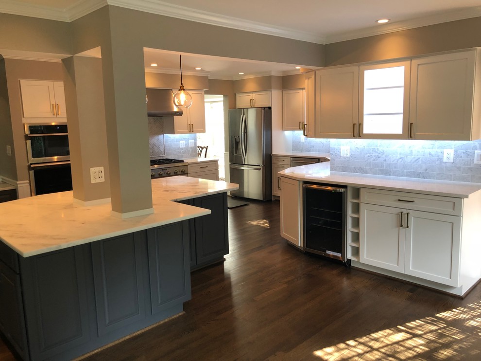 Inspiration for a mid-sized transitional u-shaped dark wood floor and brown floor eat-in kitchen remodel in DC Metro with an undermount sink, recessed-panel cabinets, white cabinets, quartz countertops, white backsplash, marble backsplash, stainless steel appliances, an island and white countertops