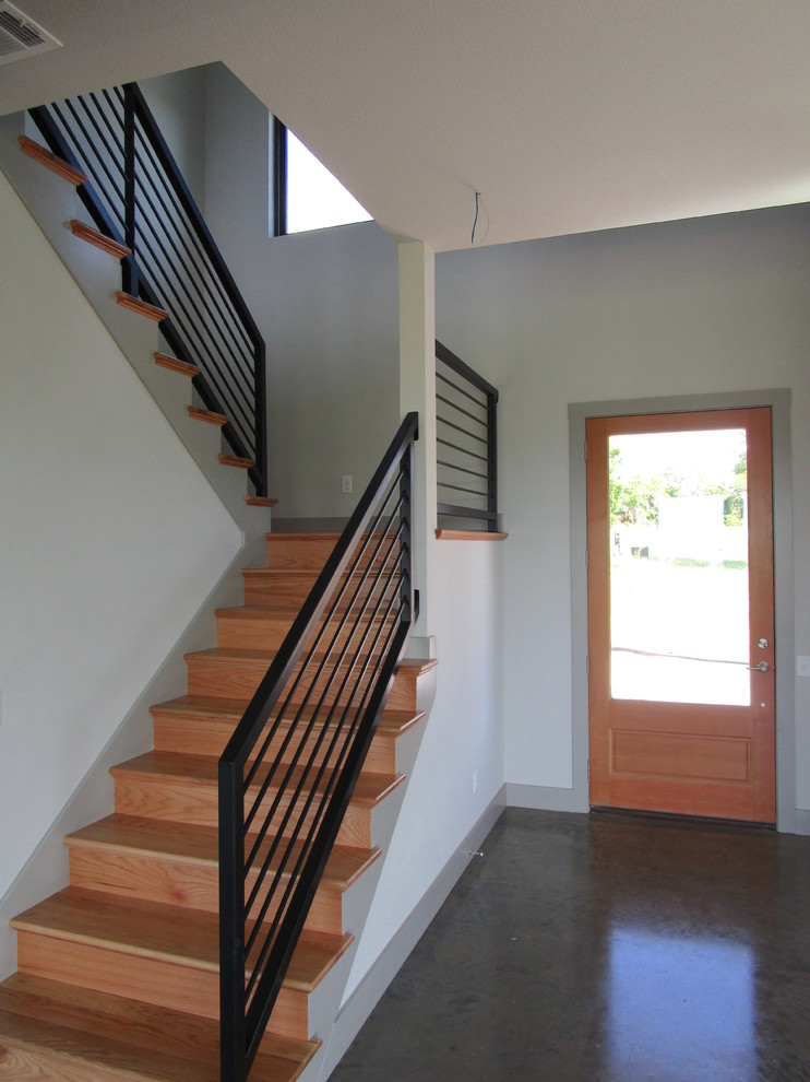 This is an example of a mid-sized contemporary wood u-shaped staircase in Dallas with wood risers and metal railing.